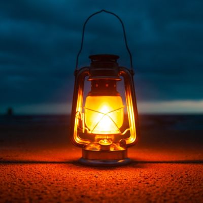 lighted kerosene lantern on the ground against a dark sky - Photo by Vladimir Fedotov on Unsplash
