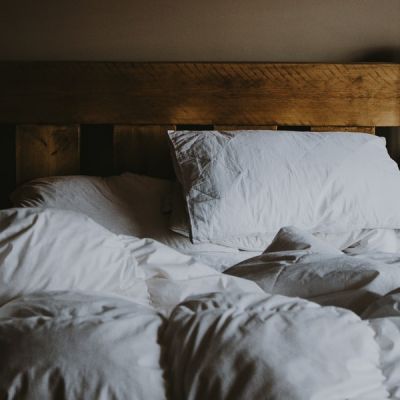 white comforter and pillow on wooden bed in darkened room - Photo by Annie Spratt on Unsplash
