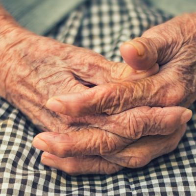 Closeup of older person's hands clasped in their lap - Photo by Cristian Newman on Unsplash