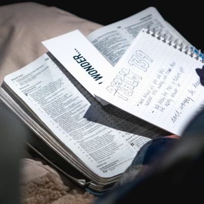 Closeup of woman holding an open bible in her lap while taking notes - Photo by Matt Botsford on Unsplash